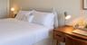 Neutral wall palette featuring a rounded upholstered headboard and wall-mounted light switches