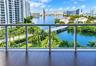 Private balcony featuring wood-finish flooring, metal railing, and expansive water and urban skyline scenery
