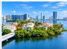 Waterfront estate featuring deep-water access, multi-story Mediterranean-style architecture, tile roofing, private bridge entry, and mature tropical l