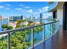 Curved balcony with wood-finish flooring, glass panel railings, and metal framing