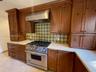 Kitchen featuring custom wood cabinetry, stainless steel professional-grade range, stainless steel vent hood, patterned tile backsplash, and light-ton