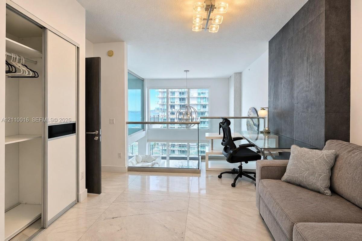 Walk-in shower featuring floor-to-ceiling neutral tile, diamond-patterned tile flooring, a wall-mounted shower head, and dual matte black wall hooks