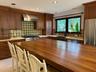 Kitchen featuring custom wood cabinetry, a large wood-topped center island, patterned tile backsplash, stainless steel range with a matching vent hood