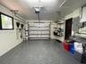 Garage featuring epoxy-coated flooring, wall-mounted metal shelving, tool storage rails, and an automated overhead door