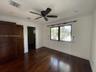 Room featuring wood-finish flooring, dark-toned wood interior doors, ceiling fan, and multi-pane window with dark-toned framing
