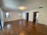 Open-concept living space featuring wood-finish flooring, recessed lighting, crown molding, and large windows with dark hardware
