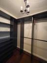 Custom storage system featuring dark wood-finish shelving and hanging rods, wood-finish flooring, and a traditional multi-arm chandelier