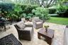 Stone paver patio featuring established perimeter landscaping, mature trees, and a grass lawn