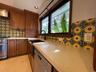 Kitchen featuring custom wood cabinetry, patterned tile backsplash, solid-surface countertops, farmhouse sink with matte black hardware, and stainless