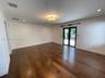 Wood-finish flooring, recessed lighting, central ceiling light fixture, and black-framed French doors