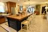 Kitchen featuring a large central island with a wood countertop, dark-finished cabinetry, stainless steel refrigerator, patterned tile backsplash, and
