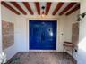 Entryway featuring double solid-panel doors with iron knockers, exposed wood ceiling beams, decorative wall tile accents, and herringbone-patterned br