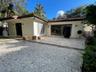 Exterior space featuring a neutral stucco finish, clay tile roof, expansive stone paver patio, multi-panel glass door systems, and decorative iron wal