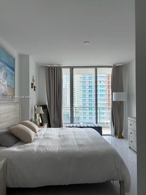 Floor-to-ceiling windows featuring access to a private balcony, polished tile flooring, and neutral wall finishes