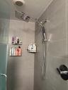 Walk-in shower featuring large-format grey tile wall cladding, an oversized square rainfall showerhead, a multi-function handheld shower wand, and a s