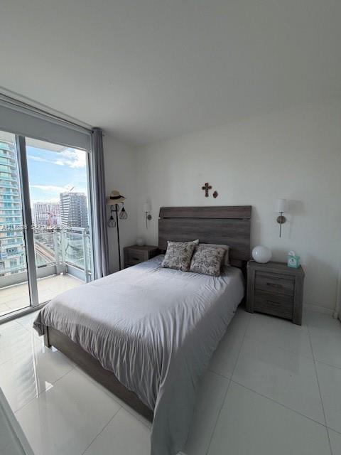 Floor-to-ceiling glass sliding doors opening to a private balcony, polished tile flooring, and wall-mounted light fixtures