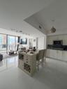 Open-concept living space featuring high-gloss tile flooring, floor-to-ceiling glass panel doors, a kitchen island with built-in wine storage, recesse