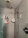 Shower enclosure featuring large-format grey wall tiling, a rainfall showerhead, a detachable hand-held sprayer, and a single-handle temperature contr