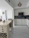 Kitchen featuring shaker-style cabinetry, stainless steel microwave, stone-finish countertops, tile backsplash, and built-in wine storage