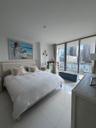 Floor-to-ceiling sliding glass doors, white tile flooring, and a private balcony