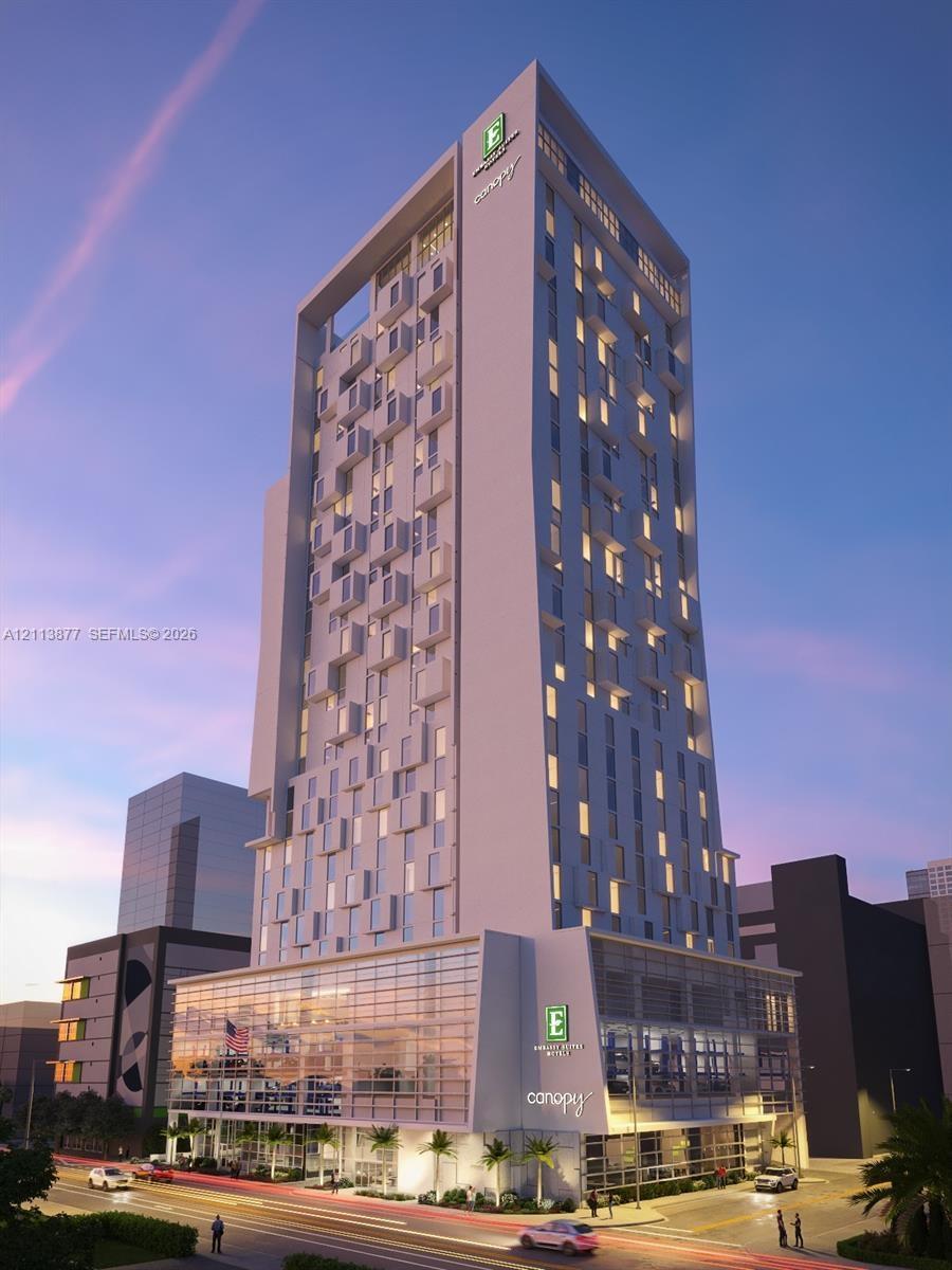High-rise commercial structure featuring a contemporary white facade, rhythmic modular fenestration, floor-to-ceiling glass paneling at the podium lev