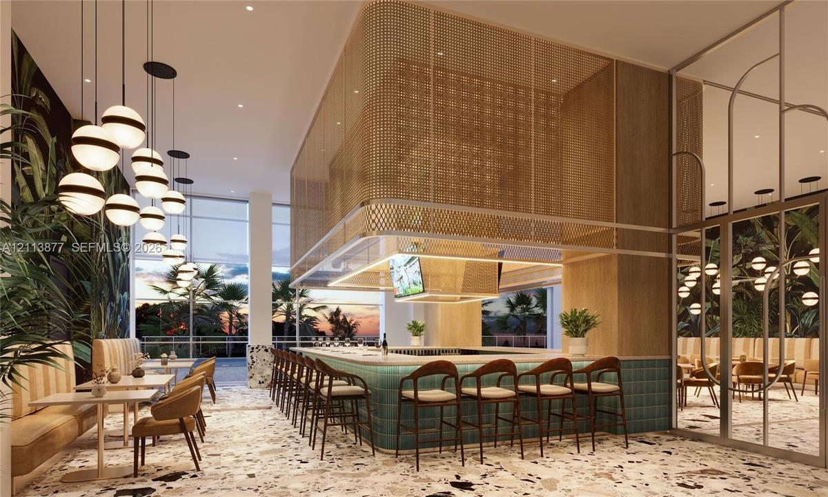 Central bar featuring a stone-topped counter with teal tile cladding, a suspended gold-tone metal mesh canopy, floor-to-ceiling glass paneling, terraz