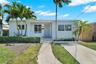 Single-story residence featuring a covered front porch, white exterior finish, concrete driveway, and mature landscaping