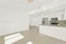Kitchen featuring white cabinetry, stone-surface countertops, stone-finish backsplash, and stainless steel appliances, complemented by large-format ti