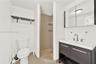 Bathroom featuring a vanity with dark cabinetry, a rectangular sink with a chrome faucet, a mirrored medicine cabinet, a walk-in shower with pebble-st