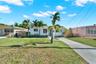 Single-story residence featuring a smooth stucco exterior, concrete driveway, and established palm trees