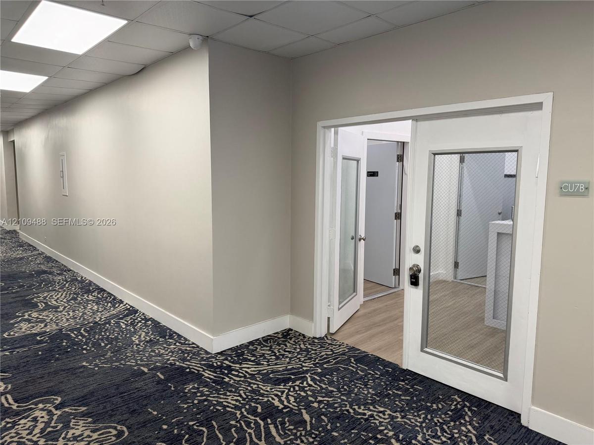 Entryway featuring a single door with a glass inlay, neutral wall paint, wood-finish flooring, and drop ceiling panels with recessed lighting