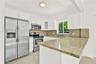 Kitchen featuring white shaker-style cabinetry, stone countertops, stainless steel appliances, and a dual-basin undermount sink