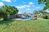 Backyard featuring a swimming pool, stone-paver decking, perimeter fencing, and mature trees