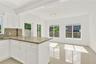 White cabinetry featuring a central island, stone-finish countertops, tile flooring, and large windows