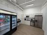 Kitchenette featuring white cabinetry, stainless steel appliances, a built-in microwave, wood-finish flooring, and high ceilings with exposed mechanic