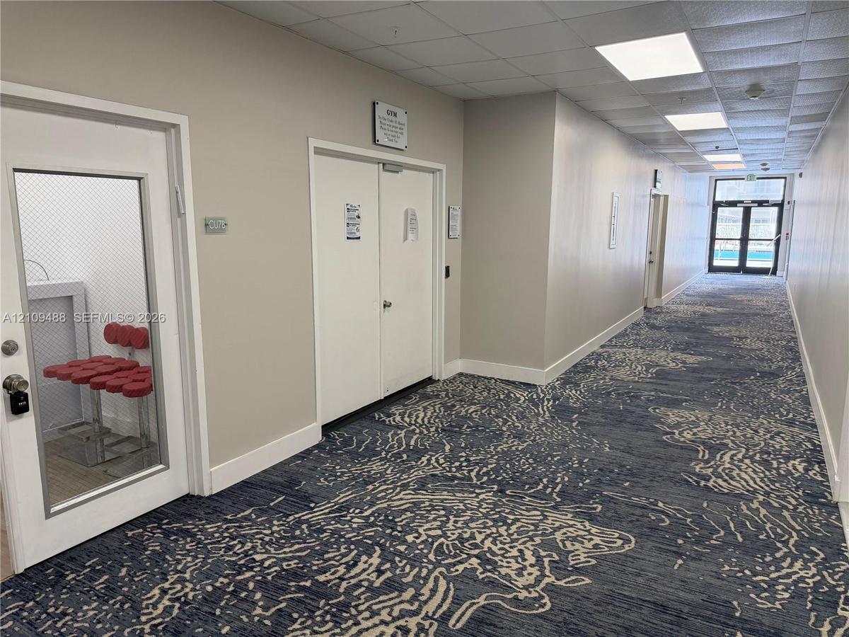 Hallway featuring patterned carpeting, recessed ceiling lighting, and multiple secure-entry doors