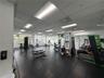 Fitness center featuring black rubberized flooring, drop ceiling with recessed fluorescent lighting, and extensive window coverage