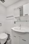 Vanity featuring a white ceramic integrated sink, chrome faucet, and built-in lower cabinetry with brushed metal hardware