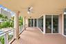 Covered terrace featuring composite decking, structural columns, ceiling-mounted fans, and sliding glass wall panels