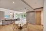 Open-concept area featuring wood-finish flooring, recessed lighting, built-in shelving, a textured stone-finish accent wall, and floor-to-ceiling glas