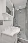 Wall-mounted medicine cabinet with mirror, pedestal-style vanity, glass-enclosed shower, wall-mounted glass shelving, and recessed ceiling lighting