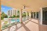 Covered balcony featuring wood-finish flooring, structural columns, white cross-pattern railings, and ceiling-mounted fans
