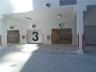Covered parking area featuring multiple rolling garage doors, concrete flooring, overhead lighting, and digital access control systems