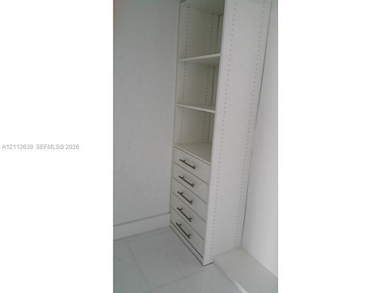 Built-in cabinetry featuring white shelving, five drawers, and metallic hardware