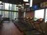 Fitness center featuring floor-to-ceiling windows, wood-finish flooring, industrial-style pendant lighting, and wall-mounted televisions