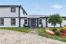 Two-story exterior featuring a white-painted brick facade with dark contrast trim, stone-clad porch columns, a multi-colored stone paver walkway, and 