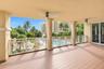 Covered balcony featuring wood-finish flooring, structural stone columns, ceiling-mounted fans, and white decorative railing