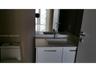 White cabinetry vanity with a light-toned countertop, integrated rectangular sink, polished metal faucet, and wall-mounted mirror