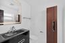 Modern vanity with an integrated sink, backlit rectangular mirror, sleek wood-finish cabinetry, and contemporary polished-chrome fixtures