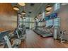 Fitness center featuring wood-finish flooring, floor-to-ceiling windows, polished wood-finish wall paneling, and industrial-style pendant lighting